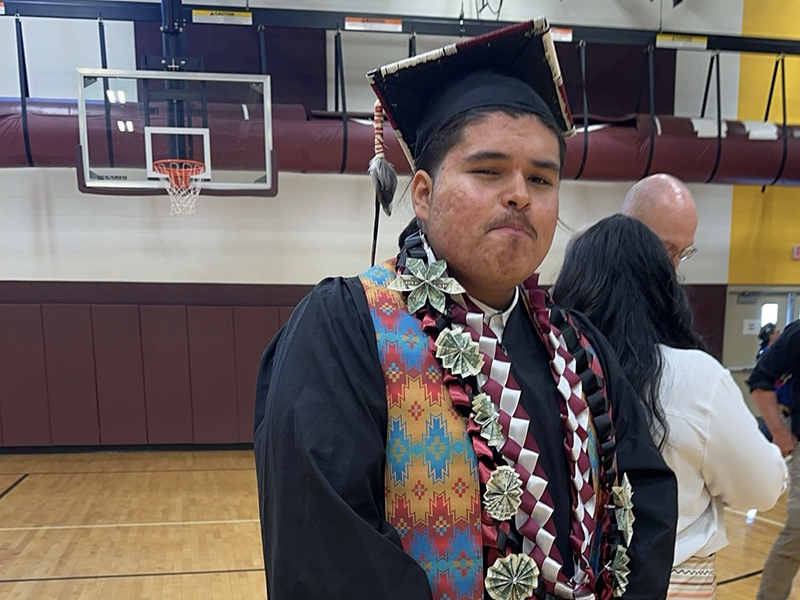 SPED student proudly smiling in his graduation cap and gown